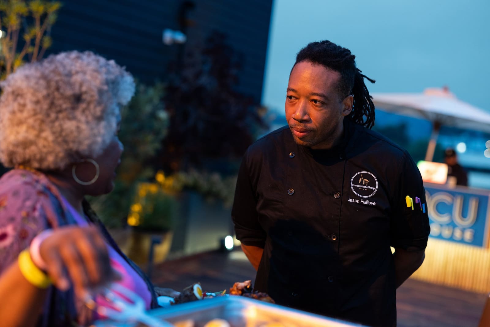 Chef Jason Fullilove talking with a guest at an evening event